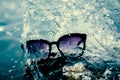 Sunglasses on a stone on a background of sea with splashes of waves