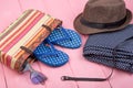 sunglasses, straw beach bag, pants, sun hat, belt and flip flops on pink wooden table Royalty Free Stock Photo