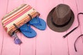 sunglasses, straw beach bag, sun hat, belt and flip flops on pink wooden table Royalty Free Stock Photo