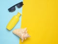 Sunglasses, sunblock, shell on a blue yellow background. Summer beach resort. Top view Royalty Free Stock Photo