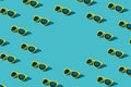 Stylish pattern of plastic sunglasses on turquoise blue background with copy space. Minimalist background of yellow sunglasses.