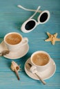 Sunglasses and two white cups of coffee on a wooden blue background. Royalty Free Stock Photo