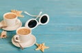 Sunglasses and two white cups of coffee on a wooden blue background. Royalty Free Stock Photo