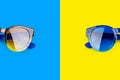 Sunglasses on vibrant blue and yellow background close up top view, fashion sunshades colorful backdrop, trendy modern eyeglasses Royalty Free Stock Photo