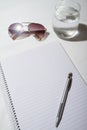 Sunglasses, water, pencil and notepad on a table from overhead Royalty Free Stock Photo