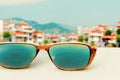 Sunglasses on a white table against the background of a southern seaside city. AI-generated image