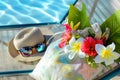 sunhat, sunglasses, and a bag of tropical blooms on a beach chair