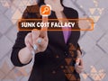 SUNK COST FALLACY inscription on the screen. Businessman hands holding black smart phone Royalty Free Stock Photo