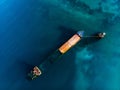Sunken cargo ship near coast of sea city, large abandoned rusty vessel in water, aerial view