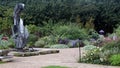 The Sunken Garden at Olbrich Botanical Gardens with flower beds, sculptures, brick walkways and a row of dense shrubbery