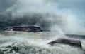A sunken old ship with a tanker on its side stranded on the seashore amidst giant waves. dramatic sky and stormy sea.