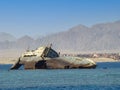 A sunken rusty ship in the Red Sea against the backdrop of mountains.