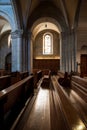 Sunlight beaming down on empty wooden church pews. Wide angle view, no people