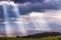 Sunlight beams over clouds in mountains. Rays in cloudy sky