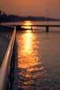 Sunlight with bokeh on water next to metal rail by the sea in Sattahip, Thailand.