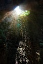 Sunlight burst or sun flare coming from top of underground cave mouth opening.