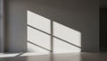 Sunlight casting geometric window pane shadows across a plain white wall and light grey floor in an empty room Royalty Free Stock Photo