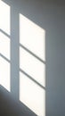 Sunlight casting geometric window shadows on a smooth gray wall Royalty Free Stock Photo