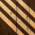 Sunlight casts diagonal shadows on a wooden surface highlighting the Royalty Free Stock Photo