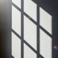 Sunlight casts geometric diamond patterns through a window onto a dark wall creating a serene abstract light and shadow Royalty Free Stock Photo