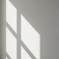 Sunlight casts geometric shadows through a window onto a light-colored wall. The Royalty Free Stock Photo