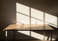 Sunlight casts grid-like shadows on a plain wall and wooden table, Royalty Free Stock Photo
