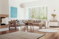 Sunlight coming through a large window into a white and beige living room interior with fruit bowls on a wooden table