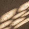 Sunlight creates diagonal shadows on a textured, beige stucco wall. The surface features irregular, Royalty Free Stock Photo