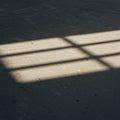 Sunlight creates a grid-like pattern on a textured dark surface, casting shadows and Royalty Free Stock Photo