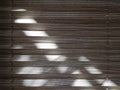 Sunlight falls on fabric blinds in the form of a corrugated sheet with horizontal stripes of gray color. Royalty Free Stock Photo