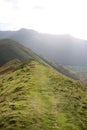 Sunlight on grassy mountain ridge footpath Cumbria