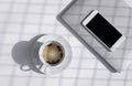 Sunlight and grid shadow pattern on surface of herbal tea in white ceramic cup with blank smart phone and grey laptop on white Royalty Free Stock Photo