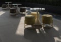 Sunlight illuminates a modern outdoor seating area, small round tables are paired with chic circular ottomans. Sharp, dramatic Royalty Free Stock Photo