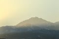 Sunlight illuminates the snow-capped high mountains of the Trans-Ili Alatau in the haze on an early winter morning