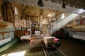 Sunlight lightens the iconostasis in the temple. A lonely grandmother sits on a bench and prays. Transcarpathia, Ukraine