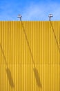 Sunlight and long shadow of spotlights on blank yellow outdoor billboard surface with blue sky