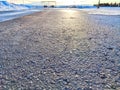 Sunlight Reflecting on a Wet Asphalt Road. Sun peeks over a ice covered road, casting a glow on the textured surface Royalty Free Stock Photo