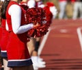 Red pom poms shimmer in the sun held by cheerleader Royalty Free Stock Photo