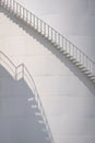 Sunlight and shadow on curved staircase surface of white storage fuel tank