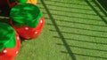 Sunlight and shadow on surface of decorative stucco garden seats in strawberry shape on artificial turf in front yard area