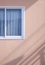 Sunlight and shadow on surface of Glass sliding window with blue curtain on pink gypsum board wall in vertical frame