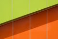 Sunlight and shadow on surface of vibrant green and orange aluminum composite tiles wall outside of modern building Royalty Free Stock Photo