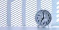 Sunlight and shadow on surface of white round table clock on white desk at morning time