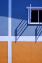 Sunlight and shadow on surface of white window in blue and orange painted wall background Royalty Free Stock Photo