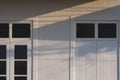 Sunlight and shadow on white wooden door and tinted glass window on gravel wall of vintage house Royalty Free Stock Photo