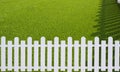 Sunlight and shadow on surface of white wooden picket on green artificial turf in front yard area Royalty Free Stock Photo