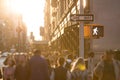 Sunlight shines on the busy crowds of anonymous people walking down the street in New York City