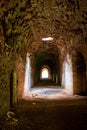 Sunlight shines through hole from brick ceiling in passage of old abandoned fort