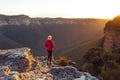 Sunlight streaming into valley and onto a cliff ledge hiker standing