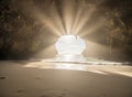 Sunlight shines through a cave opening onto a sandy beach Royalty Free Stock Photo
